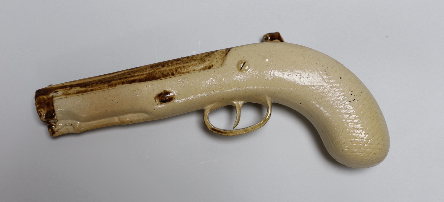 Two Georgian slip-cast Prattware figures and a Victorian salt glazed stoneware novelty pistol liquor flask, 24cm (3)